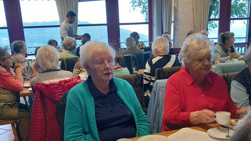 Saal mit Menschen, vorne zwei Frauen am Tisch.