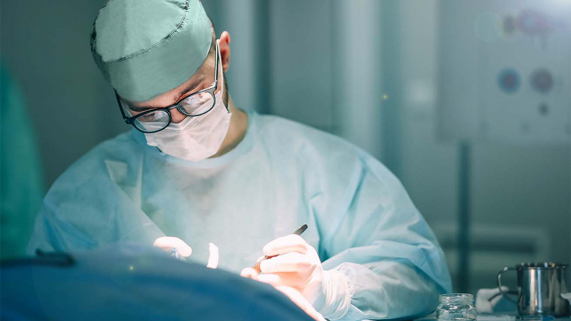 Ein Arzt operiert mit einem Skalpell an einem Patienten. 