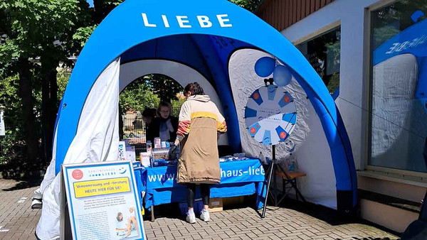 Eine Frau steht vor einem Infozelt 