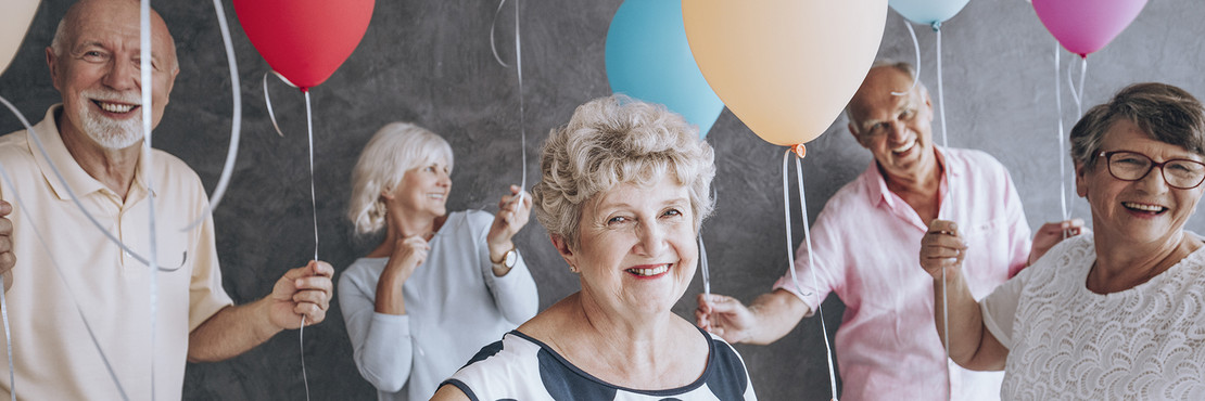 Fröhliche Männer und Frauen halten Luftballons in der Hand