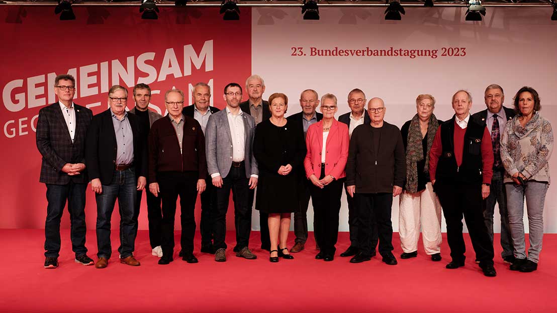 Gruppenbild mit 16 Personen auf einer Bühne