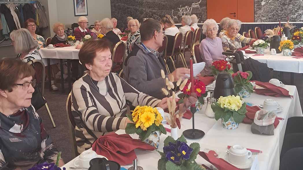 Menschen sitzen an eingedeckten Tischen.