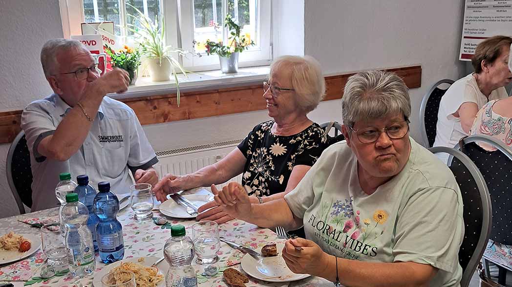 Zwei Frauen und ein Mann sitzen am Tisch und reden.