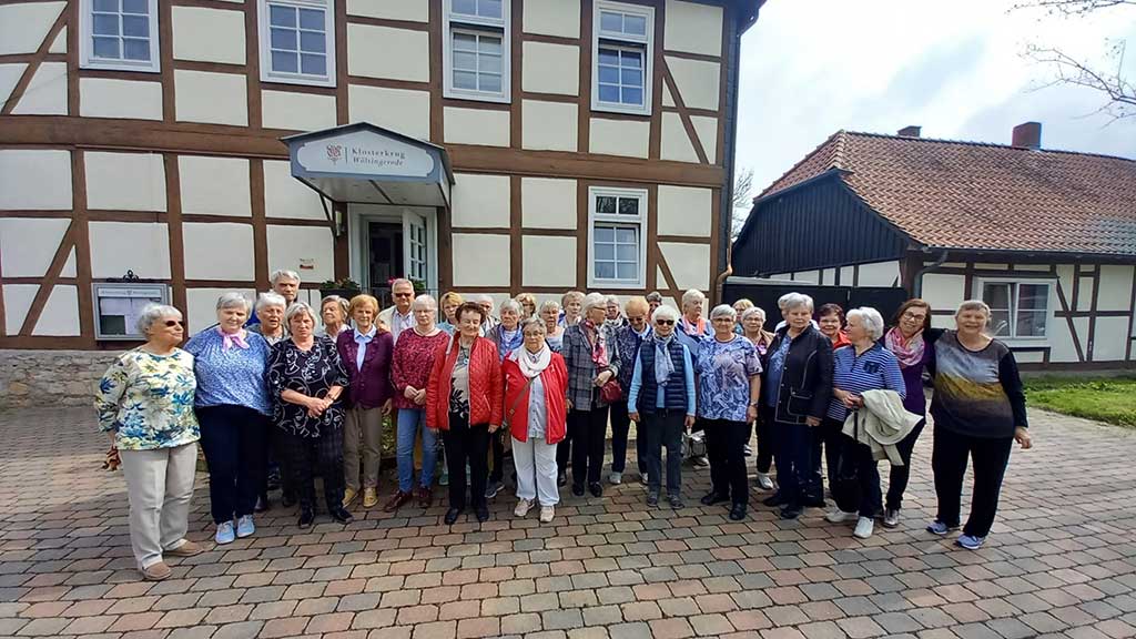 Menschengruppe vor einem Fachwerkhaus